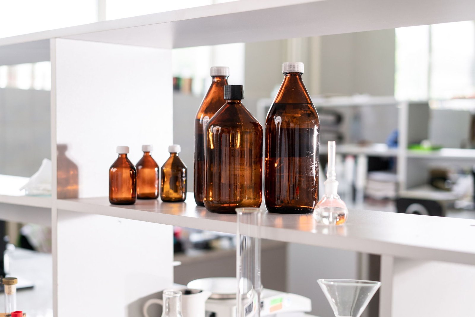 Frascos ámbar de materia prima en el estante del laboratorio